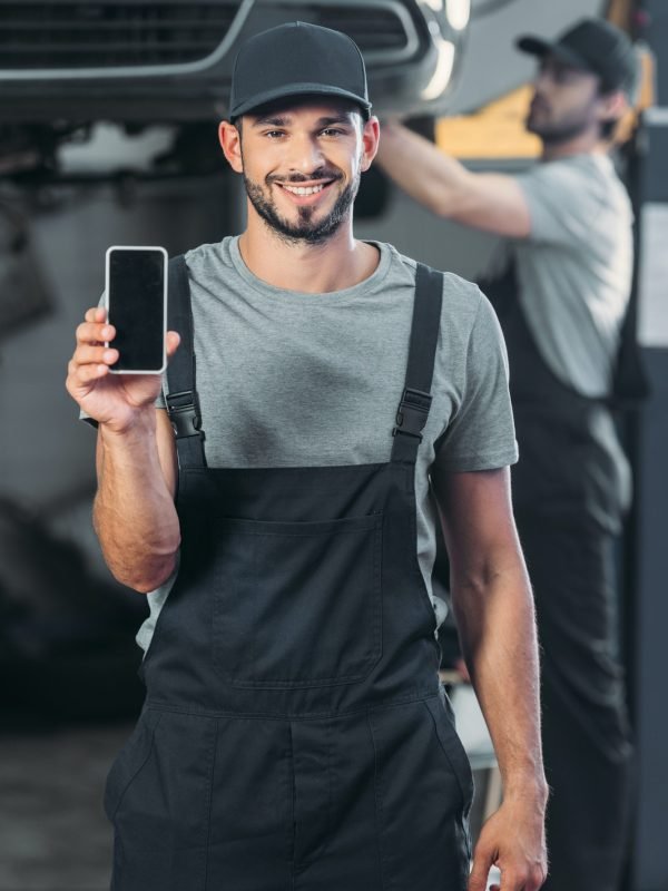 professional-mechanic-showing-smartphone-with-blank-screen-while-colleague-working-in-workshop.jpg
